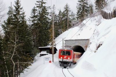 Lawinenposten
Die schlichte hölzerne Hütte am Südportal des Kleinen Klausgrabentunnels dient in schneereichen Wintern wie diesen als Lawinenposten und Fernsprechstelle. 1099 007-5 kehrt soeben mit dem Pendelzug von Gösing zurück.
Schlüsselwörter: Mariazellerbahn , MzB , Bergstrecke , Südrampe , Klausgrabentunnel , 1099