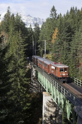 Dank der Zeitumstellung ein paar Tage zuvor steht das Motiv nun in diesen Tagen um diese Stunde im besten Licht, ohne dass die Schatten der Bäume an störender Stelle auf die Brücke und den Zug fallen würden.
Schlüsselwörter: Mariazellerbahn , MzB , Bergstrecke , Südrampe , Kuhgrabenbrücke , 1099 , Ötscherbär