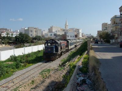 Schmalspur in Tunesien
Der Schnellzug nach Tunis verlässt das Stadtgebiet von Sousse. Im Hintergrund die Kirche St. Felix. Auf seiner Fahrt zum Zielbahnhof erreicht er 130 km/h Spitze, weltweit die höchste Geschwindigkeit auf Meterspur.
Schlüsselwörter: Schmalspur in Tunesien