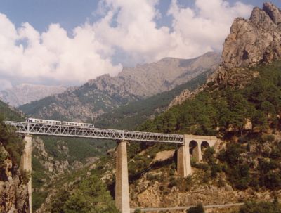 Pont du Vecchio
Der Pont du Vecchio ist eine der eindrucksvollsten Stellen im korsischen Eisenbahnnetz, das in großen Teilen als Gebirgsbahn trassiert ist. Ein Soulé- Triebwagen nach Bastia passiert soeben die Brücke.
Schlüsselwörter: Chemin de fer de la Corse