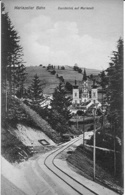 Die einzige Fotostelle mit der Basilika Mariazell befand sich an der Strecke nach Gußwerk. Das erkannten auch die Fotografen früher Postkarten, wie diese Aufnahme, die unmittelbar zur Zeit der Fertigstellung dieser Strecke entstanden sein muß, beweist. 
Postkarte aus der Zeit der Eröffnung der Bergstrecke

(Quelle: Sammlung E. Livingstone, Royston, UK)

Schlüsselwörter: Mariazellerbahn , MzB , Bergstrecke , Mariazell