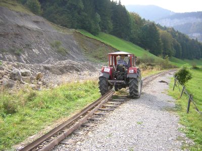 Bregenzerwaldbahn-Museumsbahn, Abbau Museumsbahnstrecke Teil Hst Bersbuch - Bf Schwarzenberg
Am 08.09.2004 musste vom Verein Bregenzerwaldbahn-Museumsbahn das Teilstück von der Haltestelle Bersbuch bis zum Bahnhof Schwarzenberg abgebaut werden, da vom Land Vorarlberg in diesem Bereich die neue Ortsteilumfahrung von Bersbuch im Zuge der L200 (Bregenzerwald-Landesstraße) projektiert war, welche 2005 eröffnet wurde.
Im Bild werden die ersten Gleise durch einen Traktor aus der ehemaligen 1-gleisigen Endhaltestelle entfernt.
Schlüsselwörter: Bregenzerwaldbahn, BWB, Wälderbähnle, Haltestelle Bersbuch, Bersbuch, Abbau